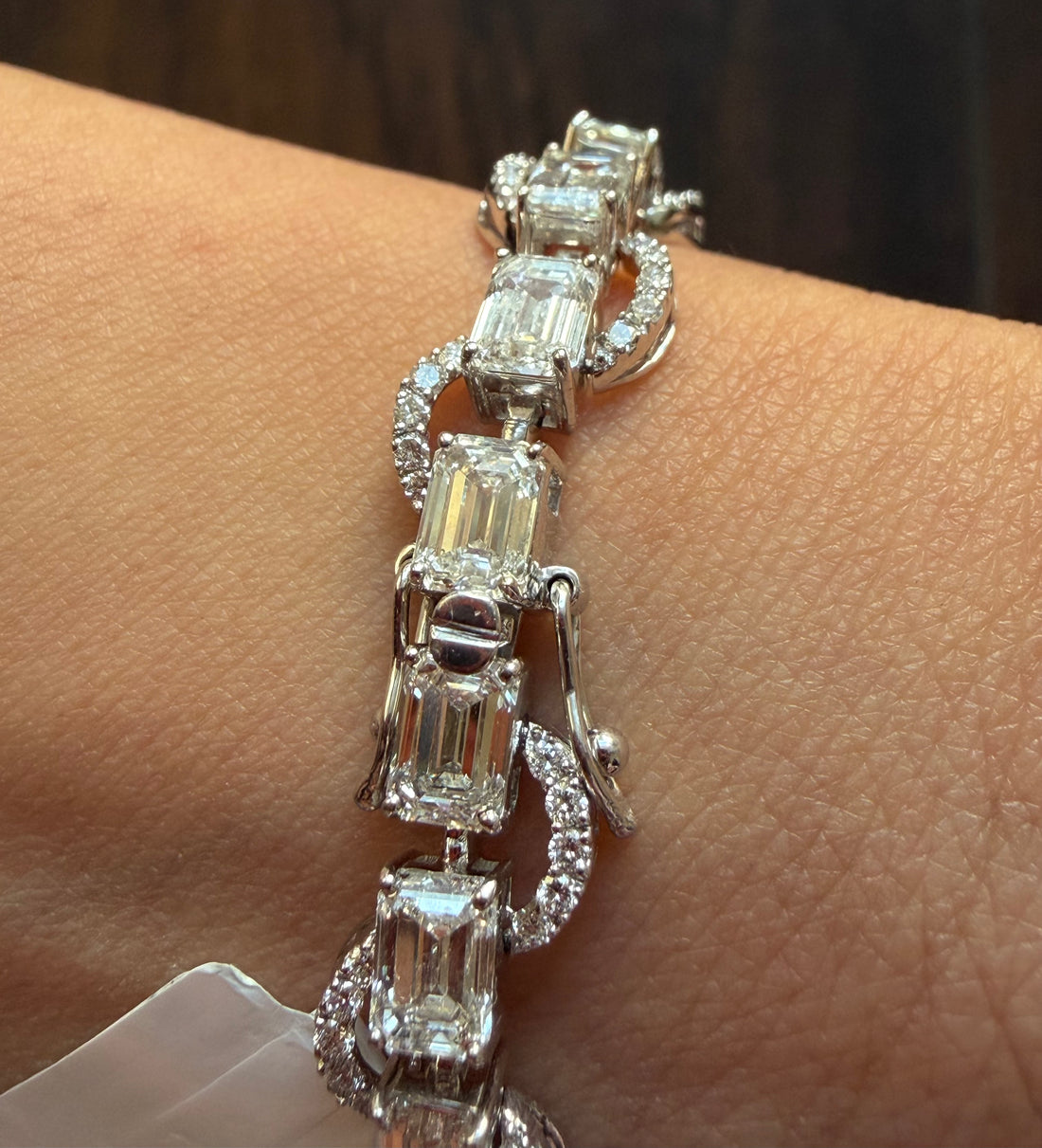 Silver bracelet with emerald-cut diamonds on a wrist against a neutral background