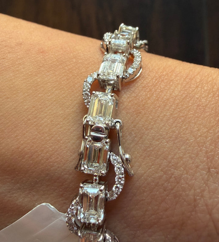 Silver bracelet with emerald-cut diamonds on a wrist against a neutral background