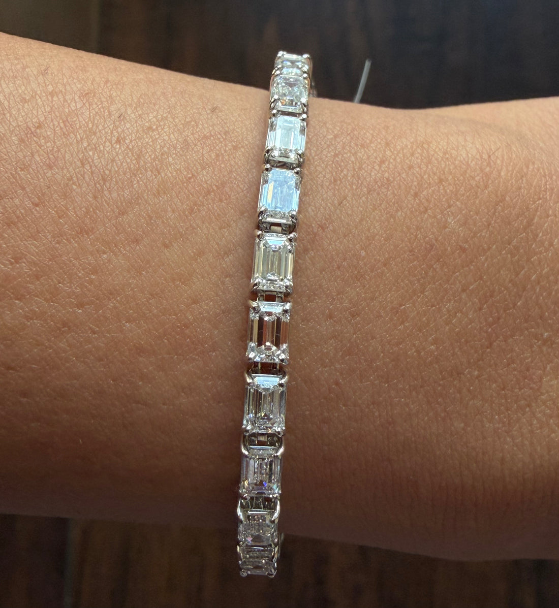 Diamond bracelet on a wrist against a neutral background