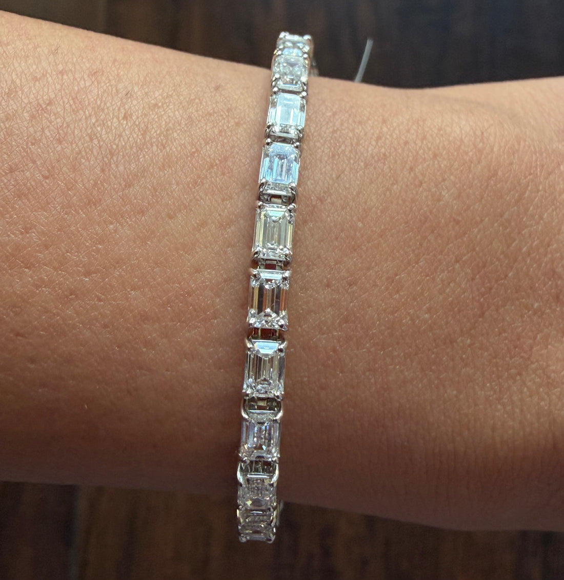 Diamond bracelet on a wrist against a neutral background