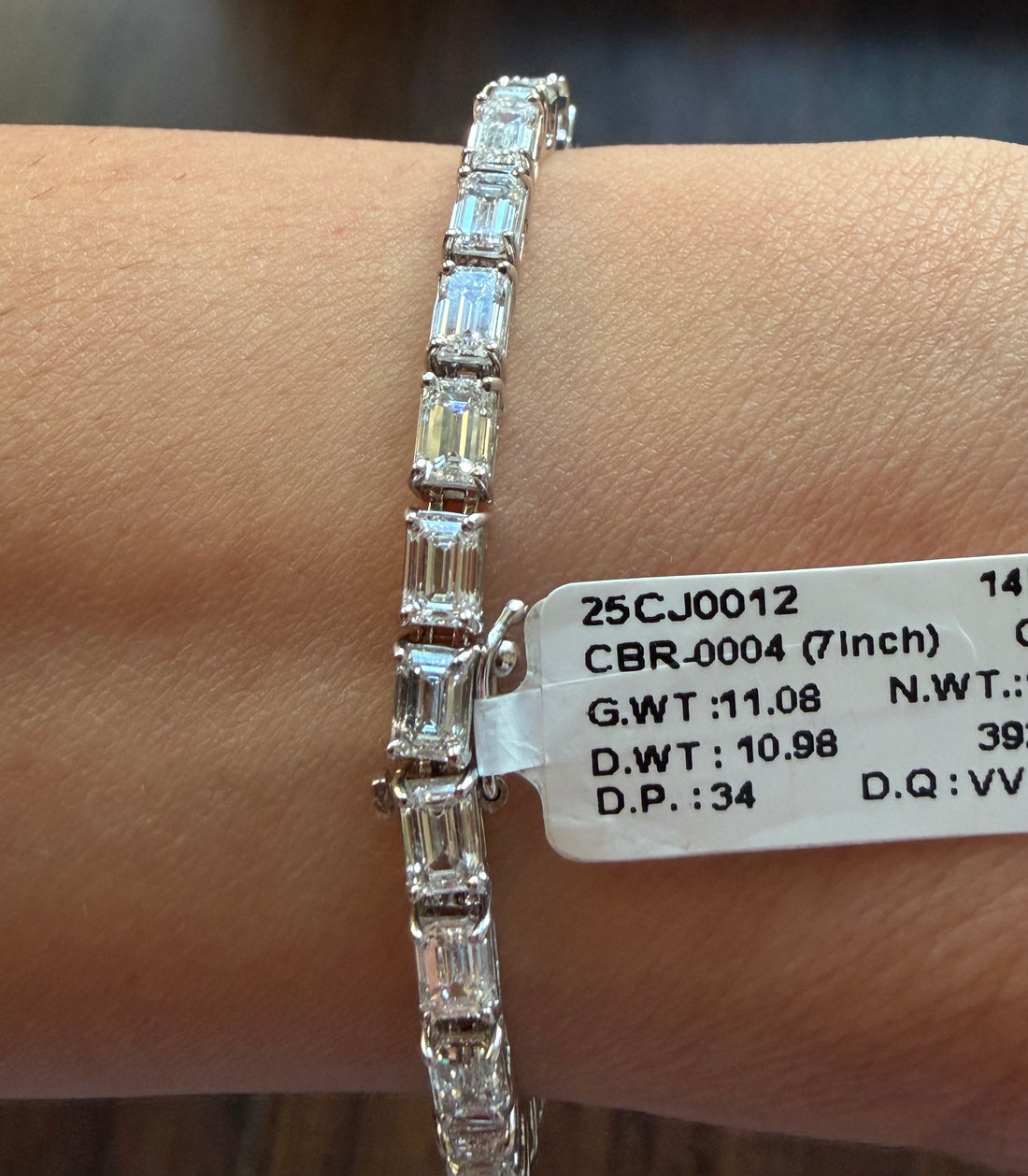 Diamond bracelet on a wrist with a label displaying jewelry details.