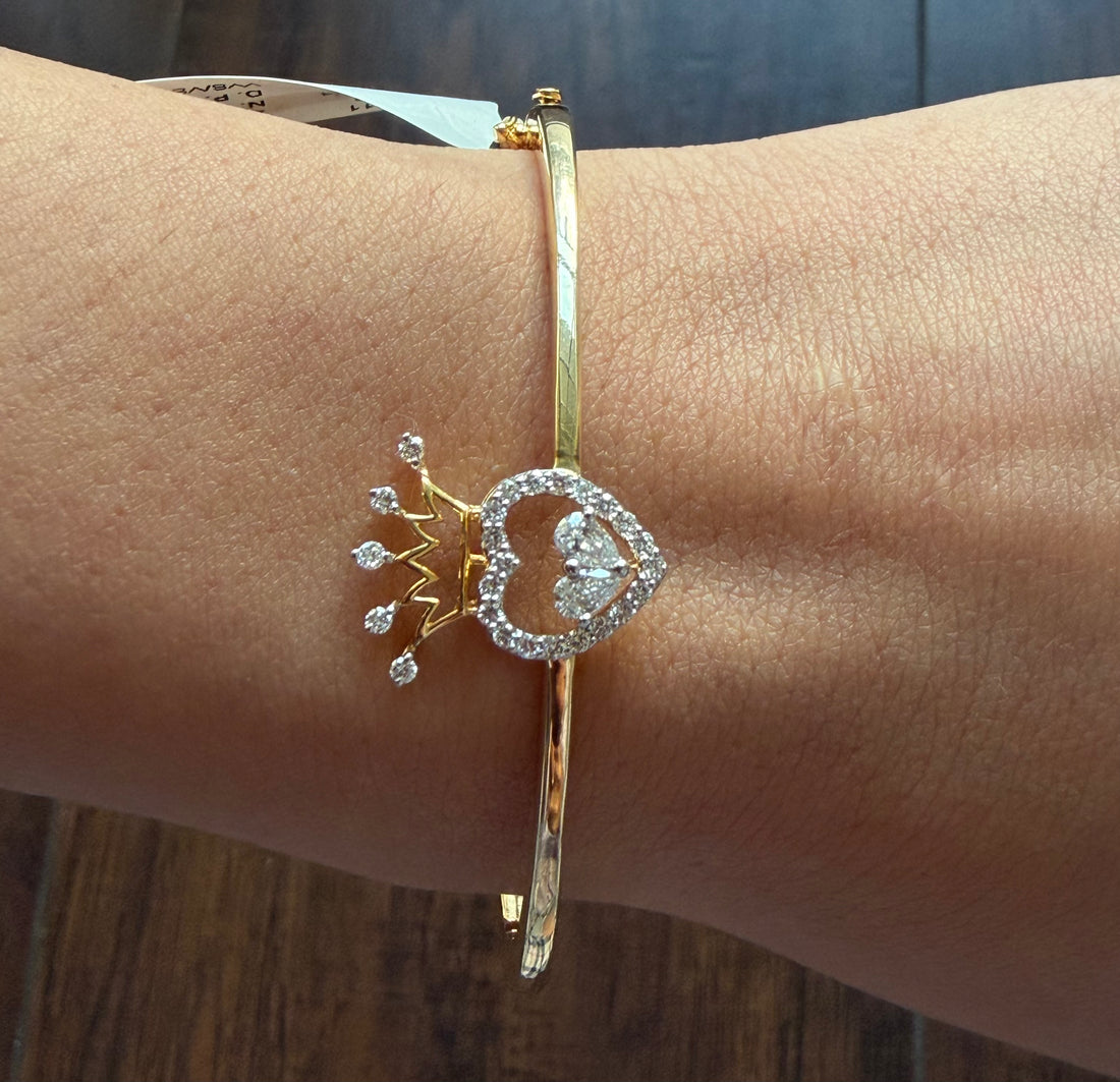 Gold bracelet with decorative elements on a wrist against a wooden background