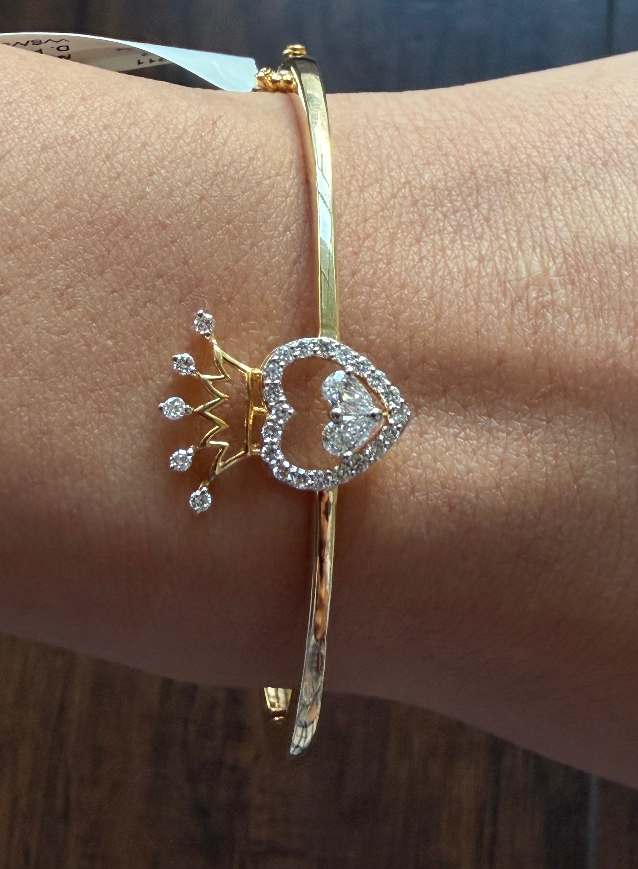 Gold bracelet with heart and crown design on a wrist
