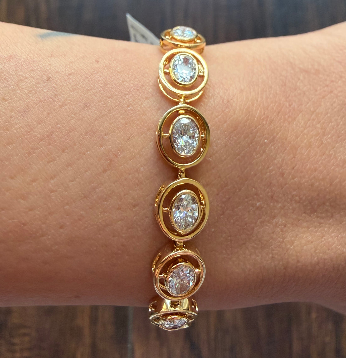 Gold bracelet with diamond-like stones on a wrist against a blurred background