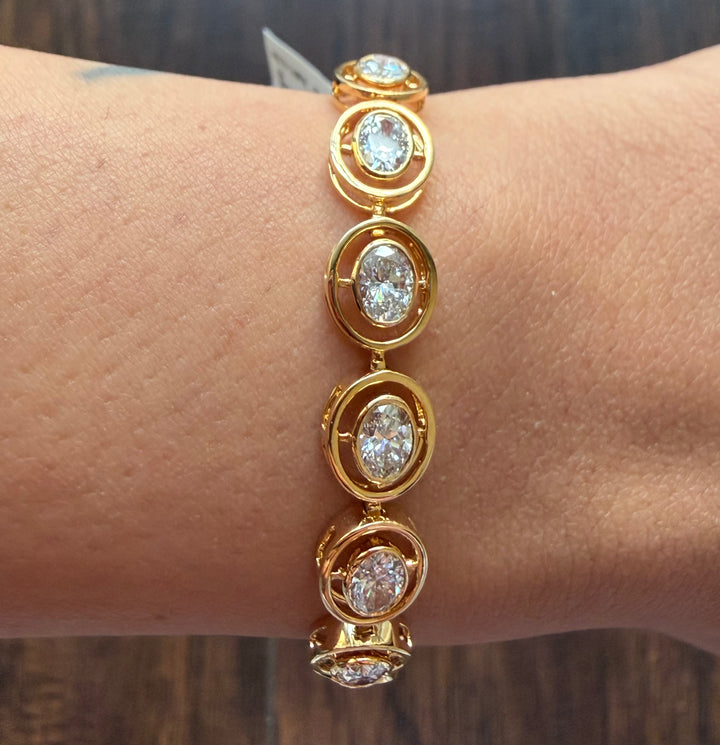 Gold bracelet with diamond-like stones on a wrist against a blurred background