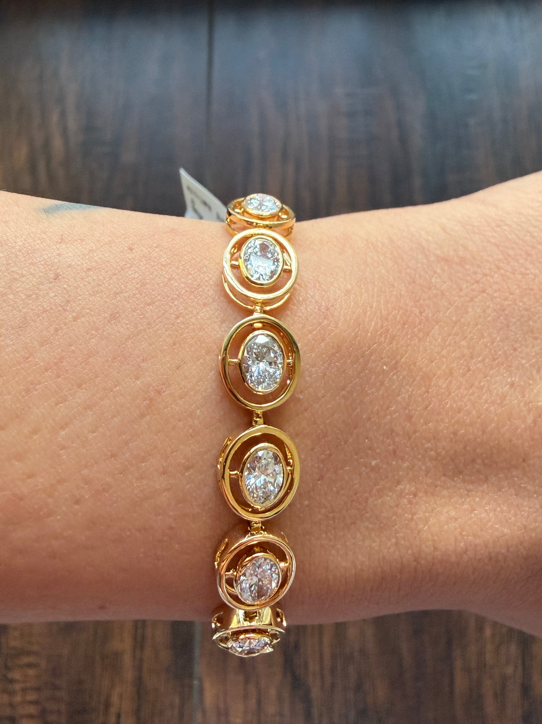 Gold bracelet with diamond accents on a wrist against a wooden background