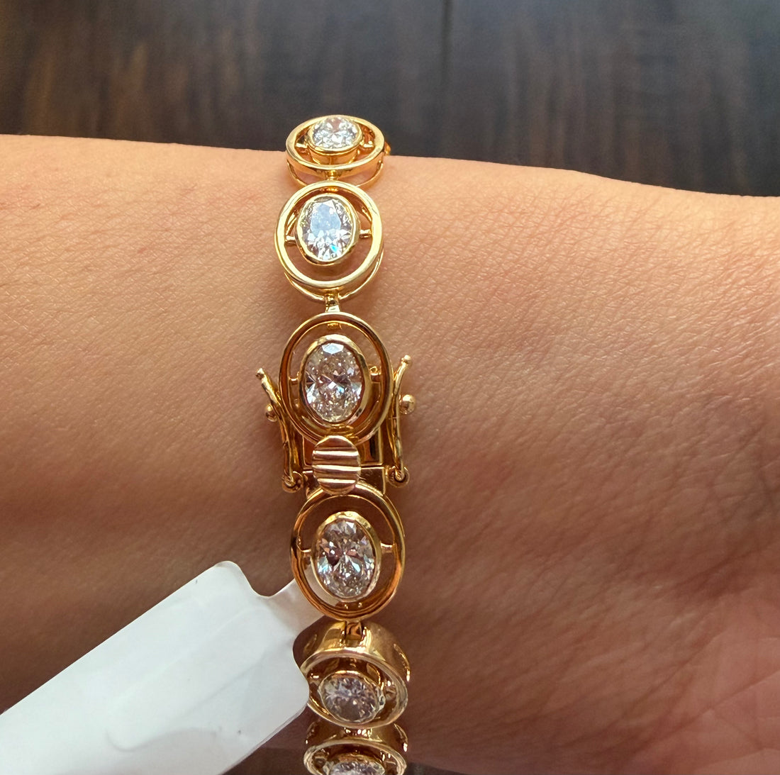 Gold bracelet with diamond accents on a wrist against a dark background