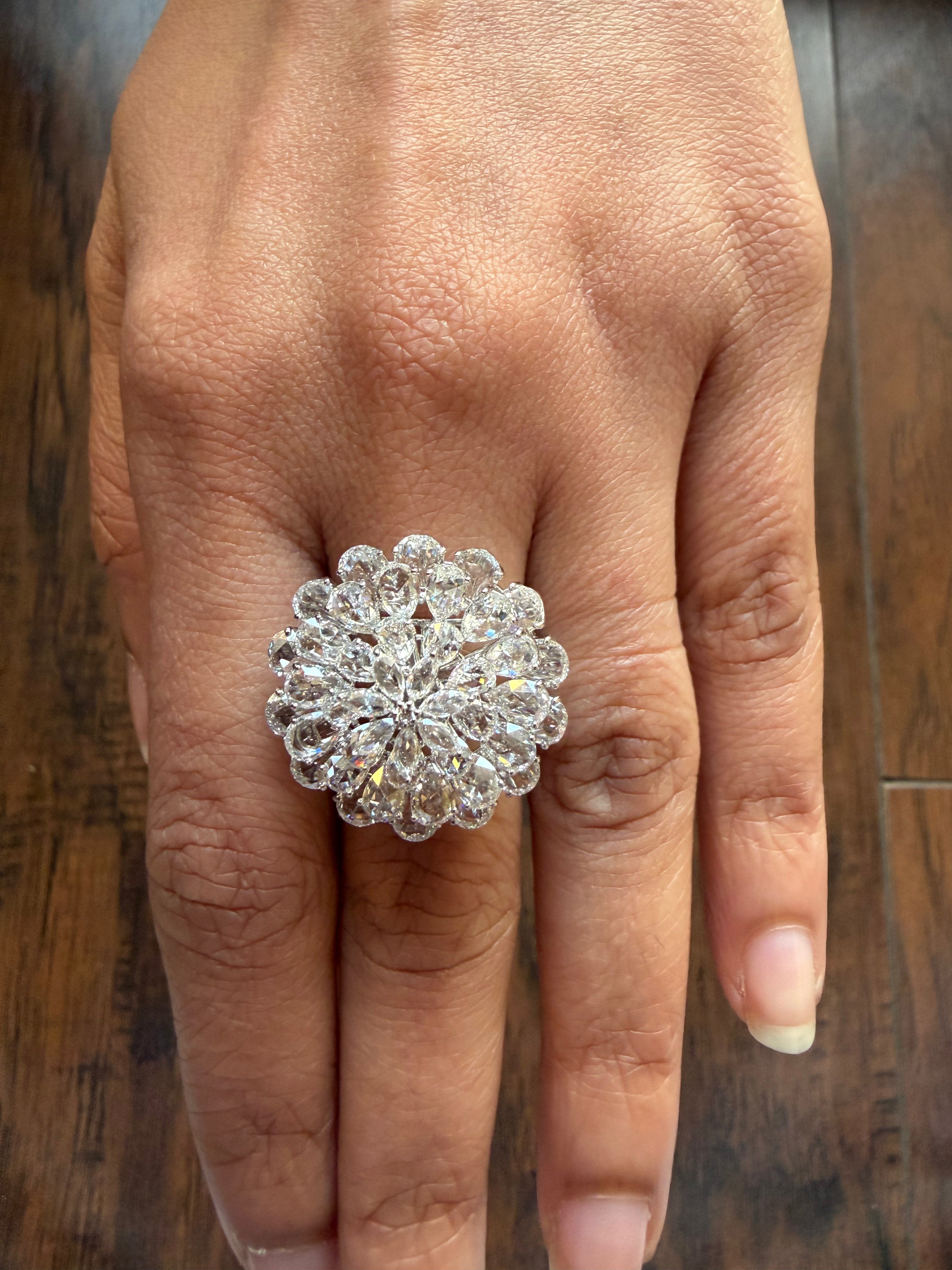 Silver ring with a floral design on a person's finger against a wooden background