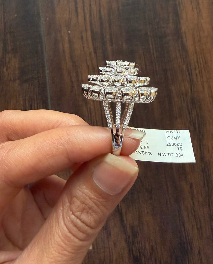 Silver ring with diamond accents held by a hand against a wooden background