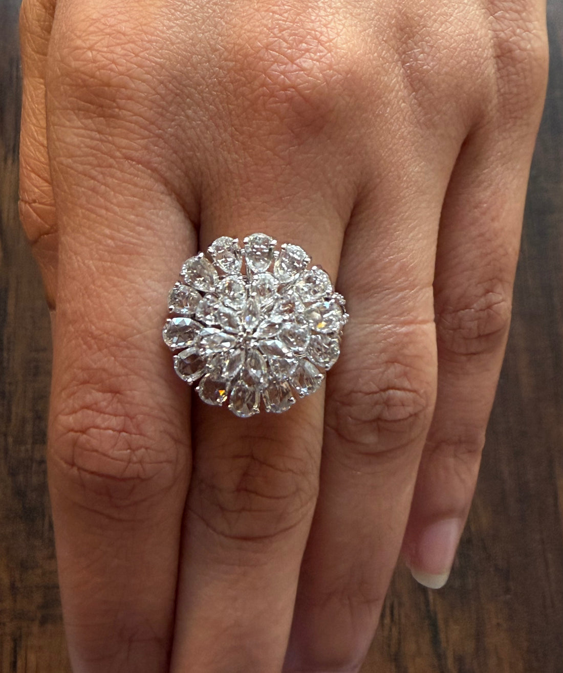 Close-up of a hand wearing a large diamond ring on a wooden surface