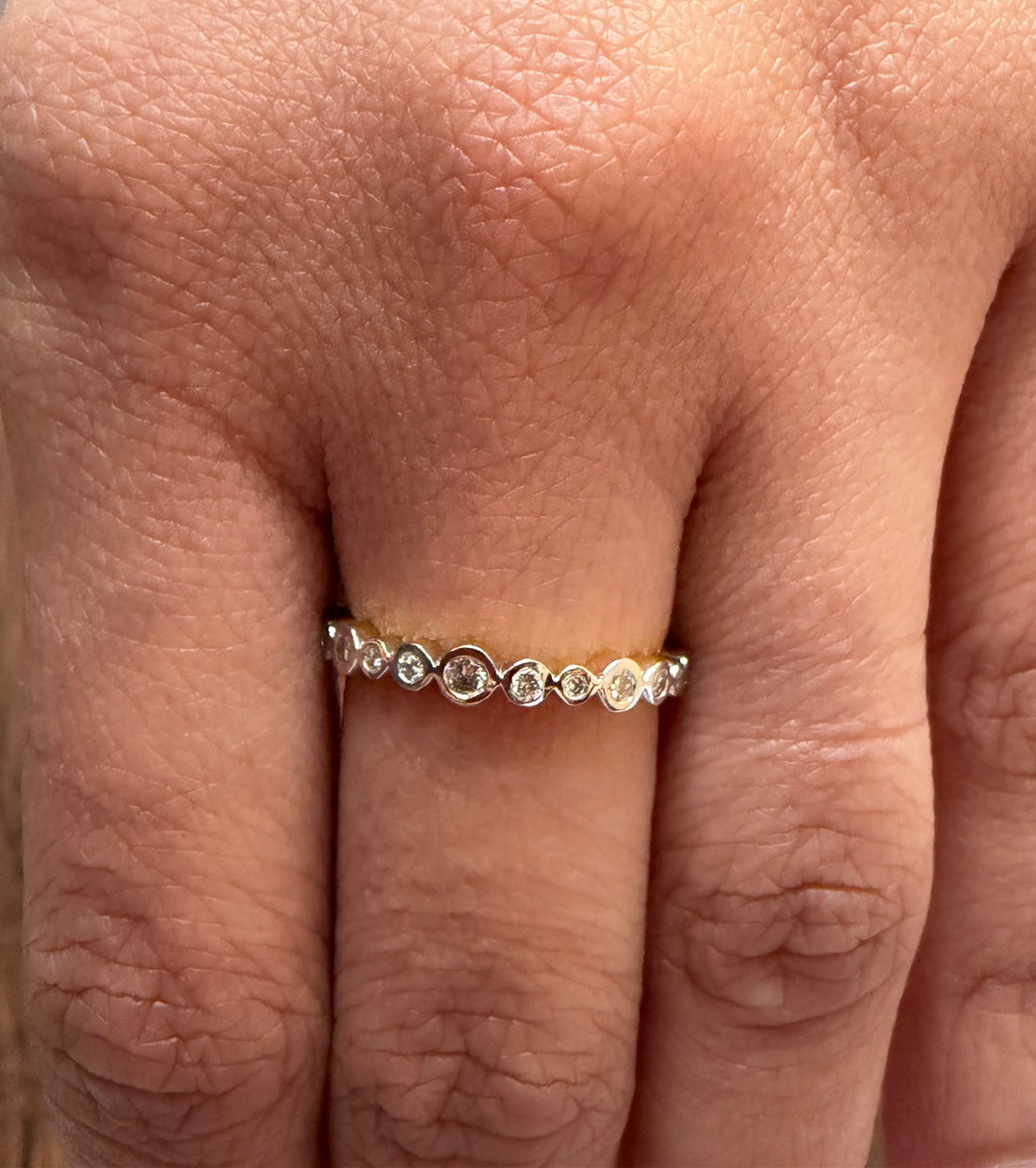 Close-up of a hand wearing a diamond ring on a light background