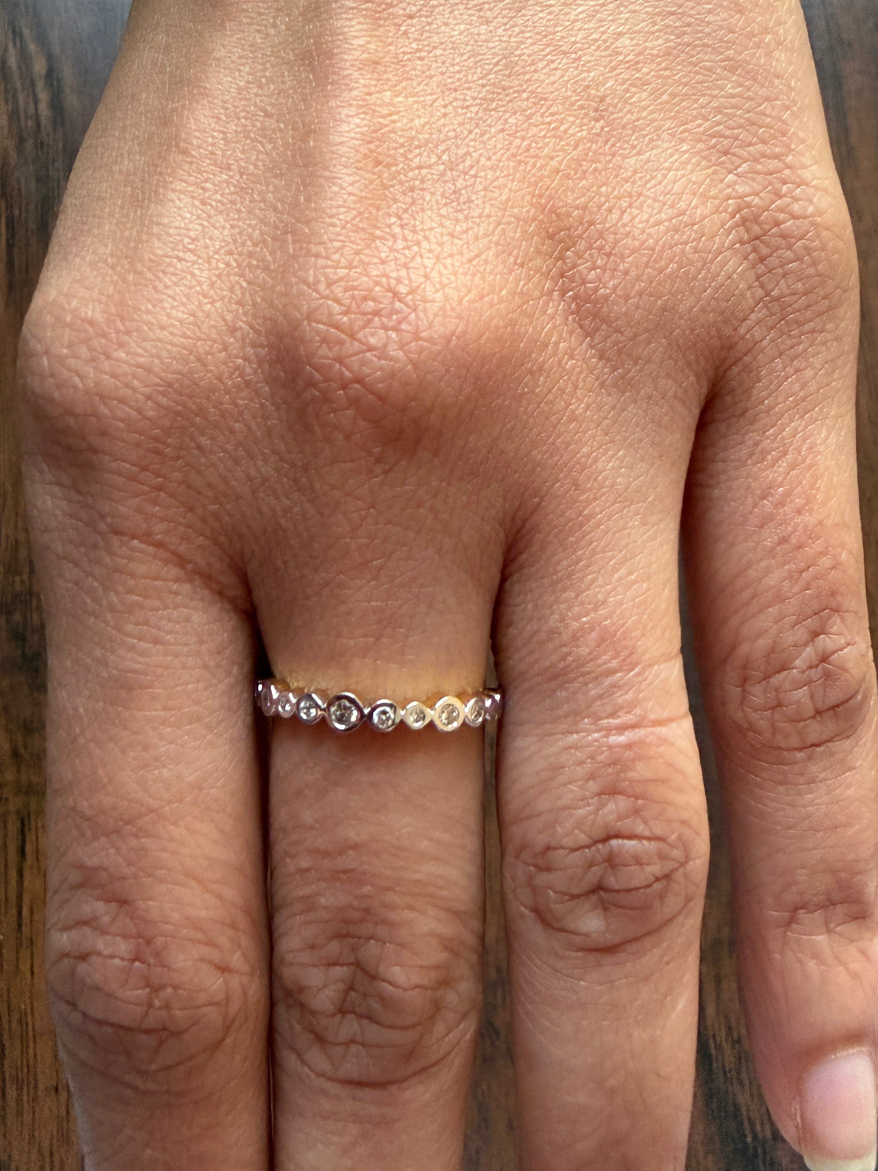 Close-up of a hand wearing a gold ring with small stones on a wooden background