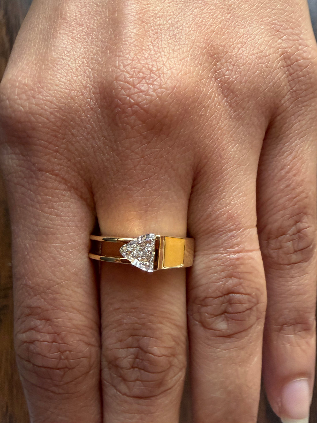 Gold ring with a heart-shaped diamond on a person's finger