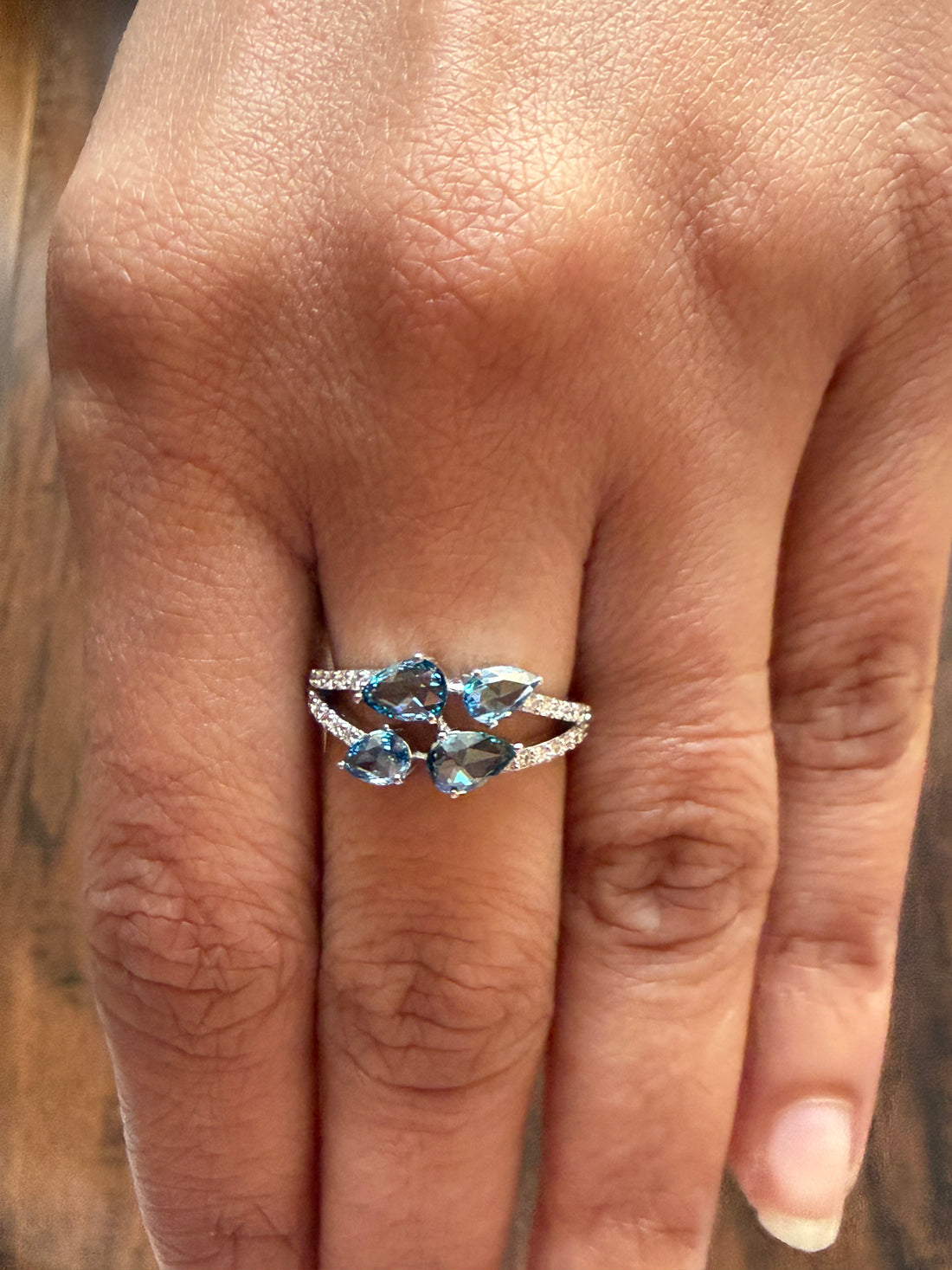 Ring with blue gemstones on a person's finger against a blurred background
