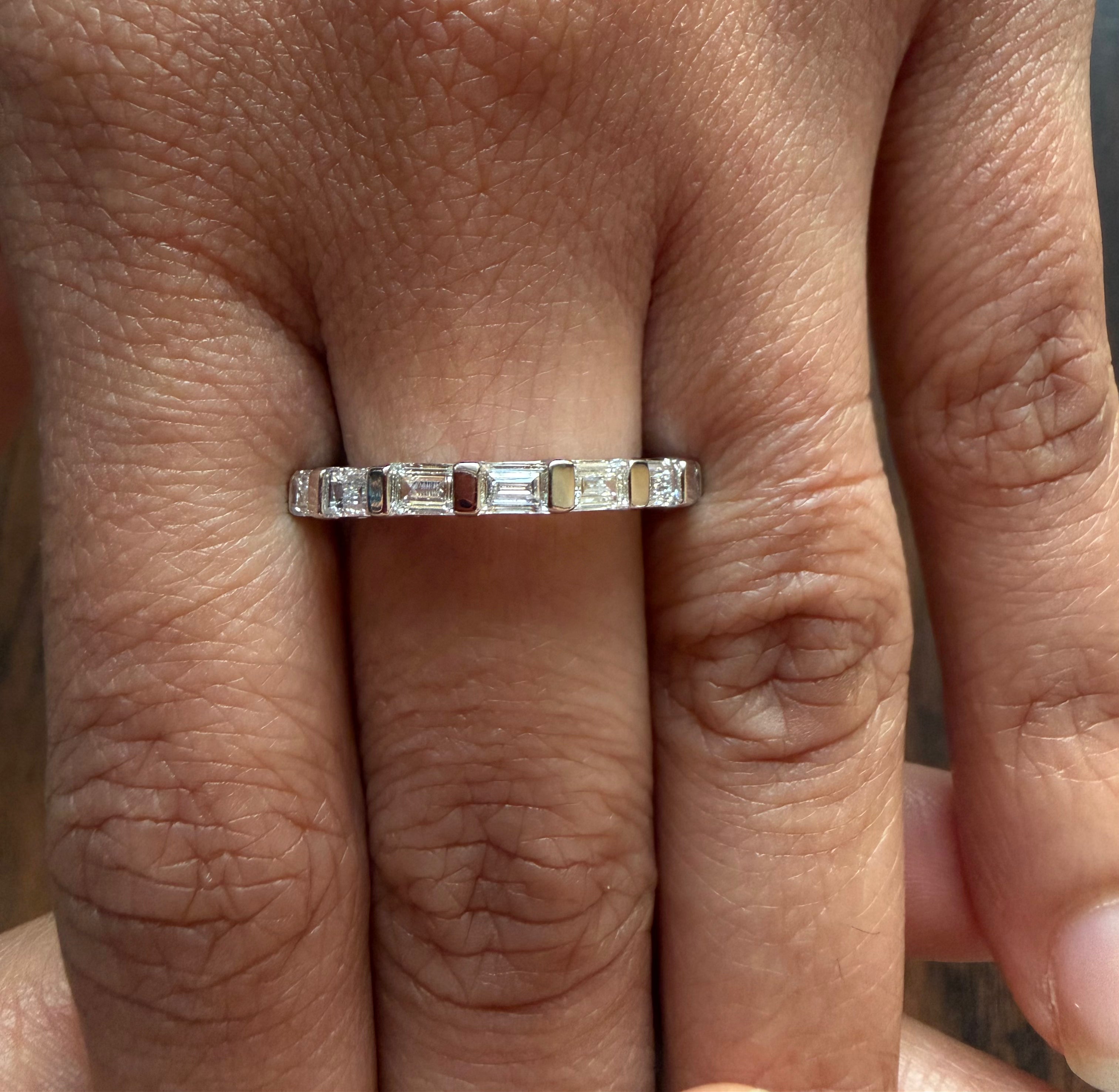 Silver ring with rectangular gemstones on a person's finger